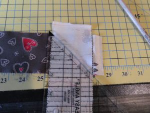 Photograph of two Jelly Roll Race quilt strips being marked to sew together on a 45 degree angle