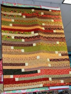 Photo of Jelly Roll Race quilt with white squares sewn in between each strip