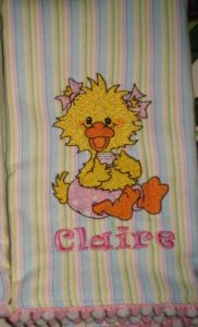 Photo of embroidered flannel burp cloth with pom pom trim on bottom