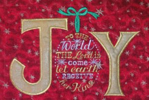 The word Joy and some of the song "Joy to the World" sewn out with metallic thread