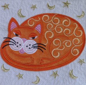 Quilt block of orange cat with gold metallic thread moon and stars.