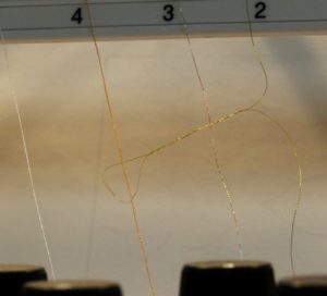 Photo of gold metallic thread twisting in the thread guides