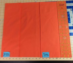 Photo of fabric for flannel burp cloth folded over 6" on one side, 9" on the other with 3" ruler placed along edge of 9" fold