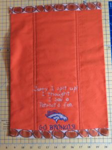 Folded flannel burp cloth with Broncos logo, text and football ribbon