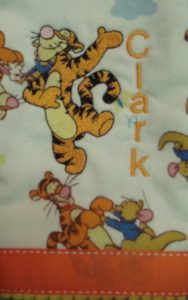 Photo of embroidered flannel burp cloth with ribbon on bottom and Tigger embroidery matching flannel print