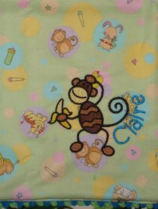 Photo of embroidered flannel burp cloth with ribbon on bottom and monkey embroidery matching flannel print