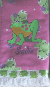 Photo of embroidered flannel burp cloth with ribbon on bottom and frog embroidery matching flannel print