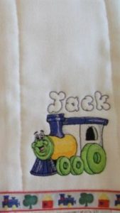 Photo of pre-folded diaper embroidered for a burp cloth featuring a train