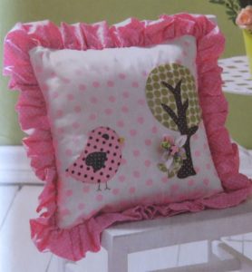 Photo of pink pillow with ruffle created by gathering fabric inserted into seam lines around the pillow