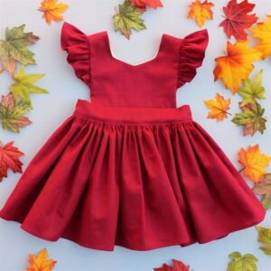 Photo of child's red pinafore dress with gathered skirt and ruffled cap sleeves