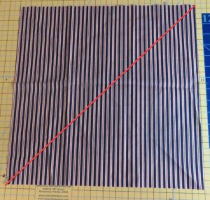 Photo of fabric with red line going from corner to corner to illustrate where to cut to make triangles