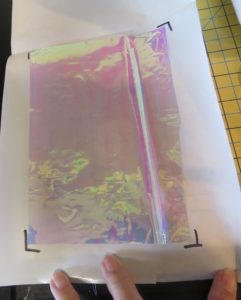Photo of clear, iridescence Mylar with waxed freezer paper marked to show position