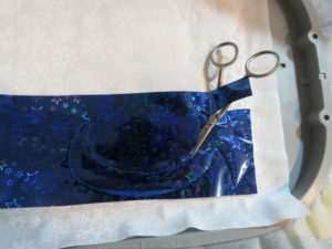 Photo of trimming away excess Mylar from around scarf tack down stitches.