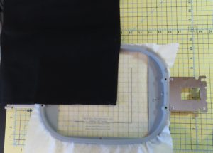 Photo of black napkin ready to be placed on hoop along stitched placement lines