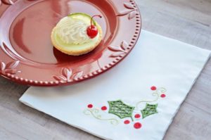 Photo of plate with white napkin with green cutwork holly from Dinner Party designs by Kimberbell, highlighted in October Sew Fun