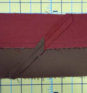 Photo of wrong side of red and brown flange binding showing seams that connect strips from end to end.