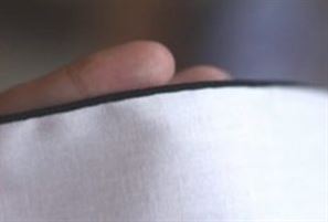 Photo of white fabric with a black thread rolled hem with textured nylon thread