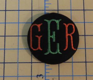 Completed covered button with monogrammed initials for square tuffet