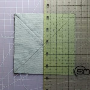 Photo of cutting sewn square at vertical midpoint to make half-square triangles