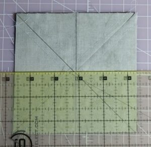 Photo of cutting sewn square at horizontal midpoint to make half-square triangles