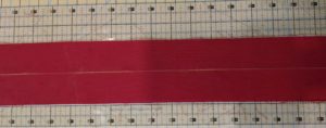 Photo of red cloth with centerline marked in yellow chalk for triple ribbon stitches headband