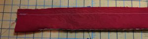 Photo of headband with right sides together and seam sewn along length.