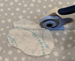 Photo of chenille cutter placed on stack of fabric to cut chenille channel