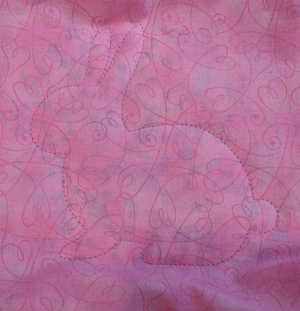Photo of pink fabric placed over placement stitch with tackdown stitch