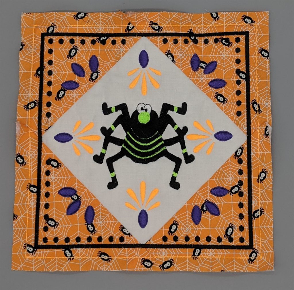 Combined embroidery design of quilt block and spider stitched out