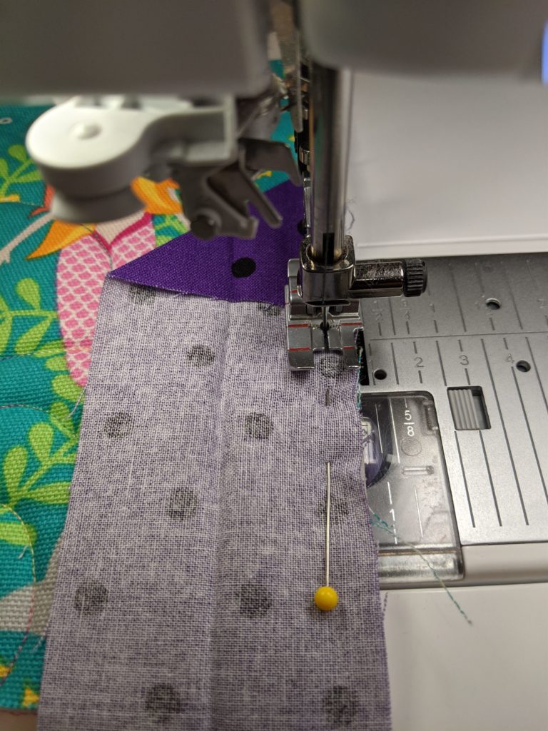 Photo of sewing down raw edge of binding to raw edge of quilt